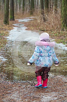 Two years old girl walking on icy puddle