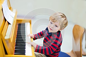 Two years old toddler boy playing piano, music schoool.