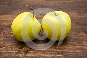 Two yellow apples on wood