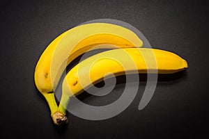 Two yellow bananas on the black background