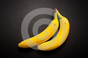 Two yellow bananas on the black background