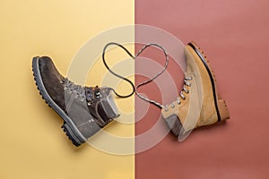 Two yellow and brown men`s and women`s winter suede leather stylish boots on color background. Laces in heart shape. Casual tren