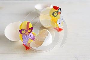 Two yellow chicken toys with glasses and eggshells on a white background