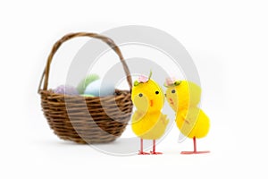 Two yellow easter chick toys with rose hats whispering in front