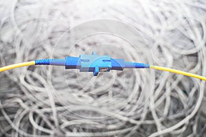 Two yellow fiber optic wires are connected to each other with an optical adapter. Cable connection in fiber networks.