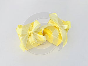 Two yellow gift boxes on white and creamy background. Aerial.
