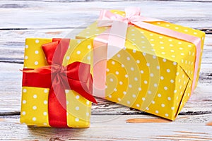 Two yellow gift boxes, wooden background.