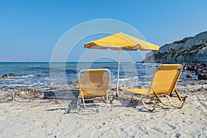 Two Yellow Lounge Chairs On The Beach By The Sea