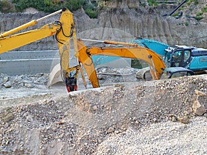 Two yellow and one blue excavators in the ditch at the site of the road construction works