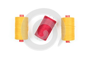 Yellow and red sewing thread coils on white background