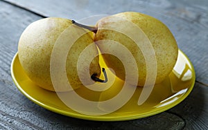 Two yellow pears on the plate on a table