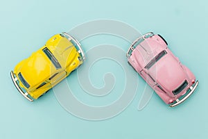 Two yellow pink vintage retro toy car isolated on blue pastel colorful background
