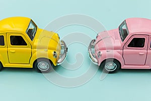 Two yellow pink vintage retro toy car isolated on blue pastel colorful background