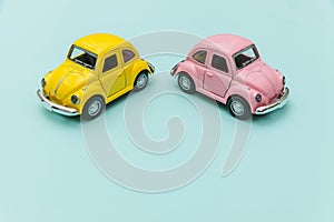 Two yellow pink vintage retro toy car isolated on blue pastel colorful background