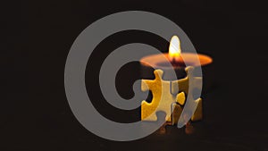 Two yellow puzzles standing against a candle.