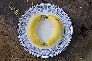 Two yellow ripw cavendish bananas in ceramic dish