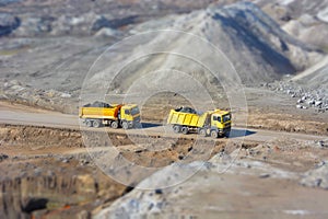 Two yellow trucks in a coal mine