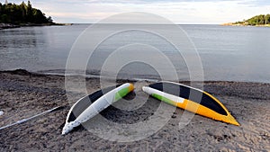 Two yellow, white and green canoes placed upside down on the beach to dry after a row