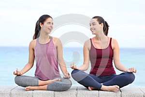 Two yogis talking doing yoga on the beach