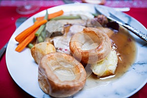 Two Yorkshire puddings on a plate of Christmas roast dinner.