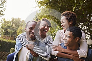 Two young adult black couples having fun piggybacking photo