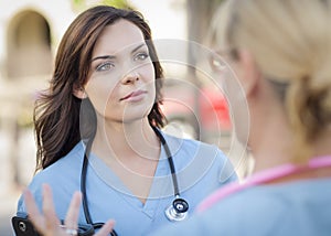 Two Young Adult Female Doctors or Nurses Talking Outside