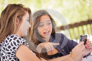 Two Young Adult Girlfriends Using Their Smart Cell Phone