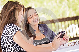 Two Young Adult Girlfriends Using Their Smart Cell Phone