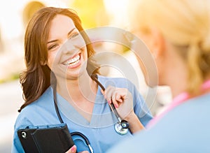 Two Young Adult Professional Female Doctors or Nurses Talking Outside.