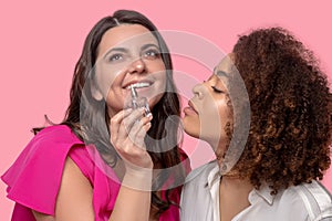 Two young adult women trying to hear a fragrance.