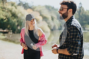 Two young adults, best friends, having a carefree conversation in a park, enjoying nature on a sunny day.