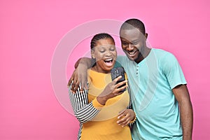 two young african friends, boy and girl, looking excited while viewing something on their smartphone together