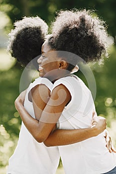 Two young afro-american sisters hugging in a park