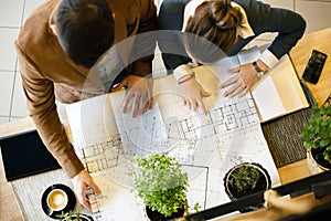 Two young architects discussing building plans during a meeting in an office