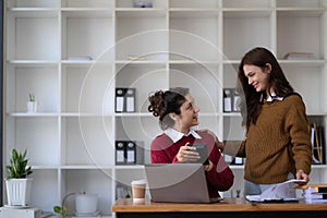 Two young Asian business woman talk, consult, discuss working with new startup project idea presentation analyze plan