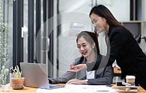 Two young Asian business woman talk, consult, discuss working with new startup project idea presentation analyze plan marketing