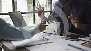 Two young asian businessmen in suits discussing financial market data in office Business team working