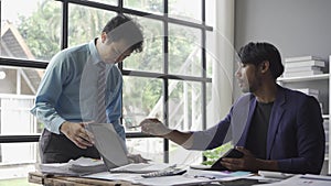 Two young asian businessmen in suits discussing financial market data in office Business team working