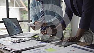 Two young asian businessmen in suits discussing financial market data in office Business team working