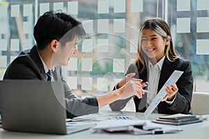 Two young Asian businessmen and women working together meet at the Financial Graphing Computing Office. Share ideas, discuss and t