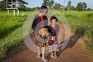 Two young Asian girls dressed according to local traditions are walking, chatting happily and smiling on the road