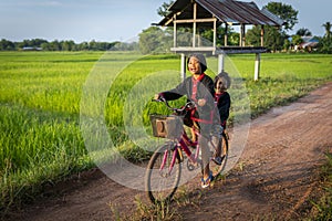Two young asian girls dressed up according to local traditions and Ride a bicycle with fun expressions and smiles, on the road