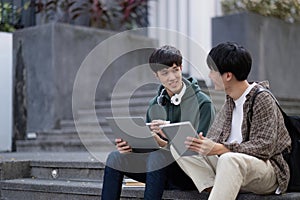 Two young Asian male college students discussing and working on their school project together