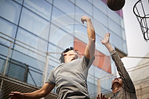 Two young asian men playing basketball