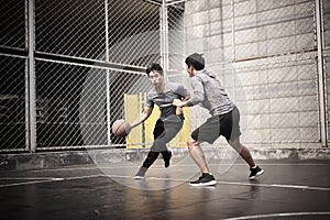 Two young asian men playing basketball outdoors