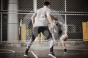 Two young asian men playing basketball outdoors