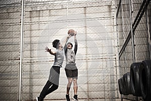 Two young asian men playing basketball outdoors