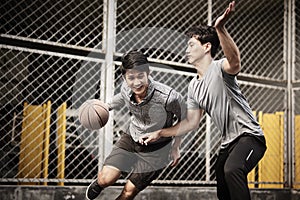 Two young asian men playing basketball outdoors