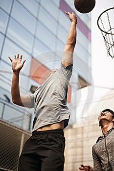 Two young asian men playing basketball outdoors