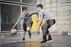 Two young asian men playing basketball outdoors